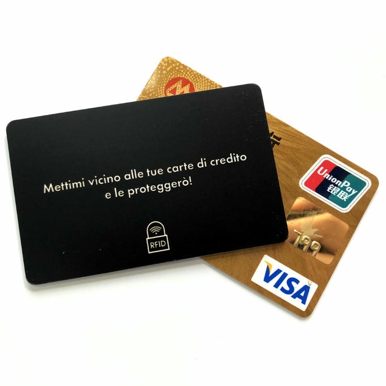 Черна RFID блокираща карта с италианско послание лежи върху златни платежни карти за да илюстрира защитата на пътни документи и карти.