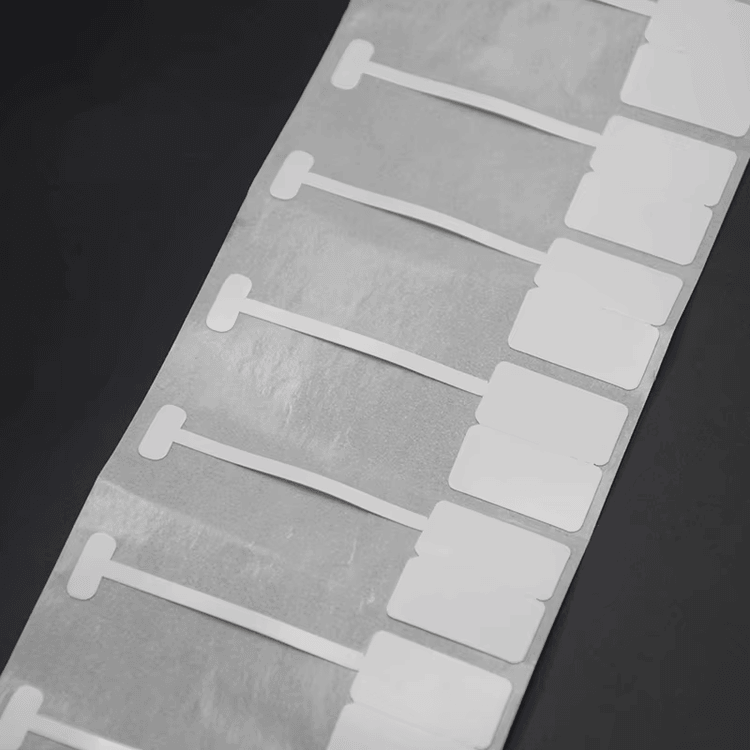 Лист с празни RFID етикети за бижута, подредени в редове, показва повторяемото оформление на тага и подложния материал.