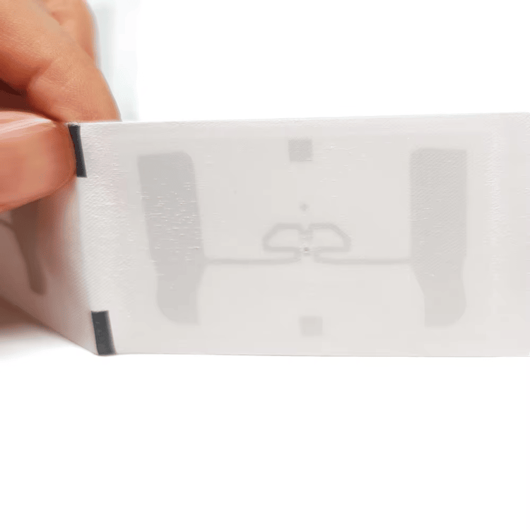 Близък хоризонтален изглед на белия тъкан RFID етикет за пране показва вградената структура на антената вътре в готовия текстилен етикет.