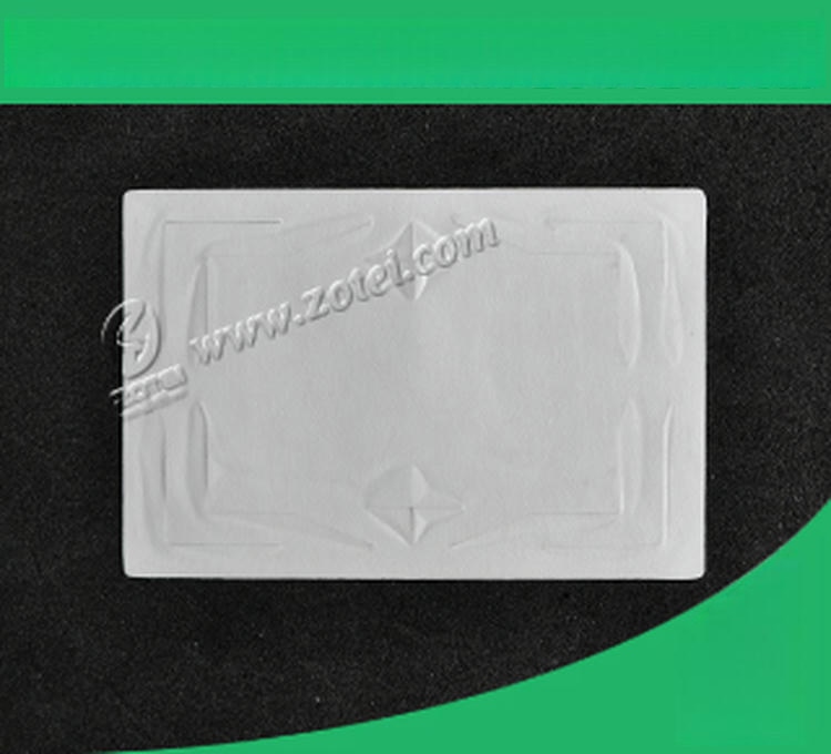 Единичен празен UHF RFID таг за предно стъкло лежи плътно върху черен фон със зелени ъгли подчертаващи гладката повърхност и релефа на антената.