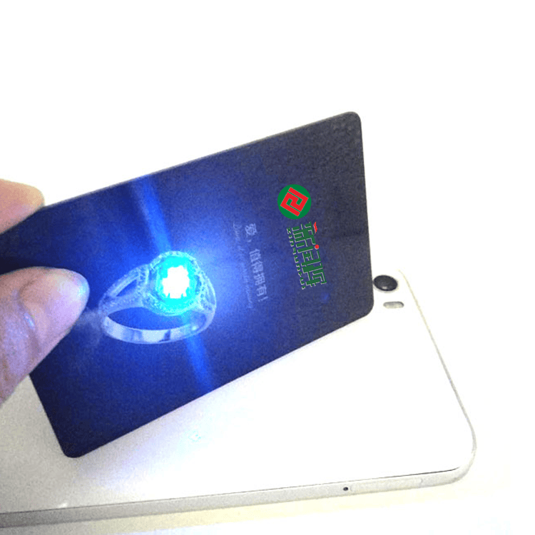 NFC карта с LED светлина, показана отблизо при доближаване до телефон, като синият индикатор потвърждава прочитането.