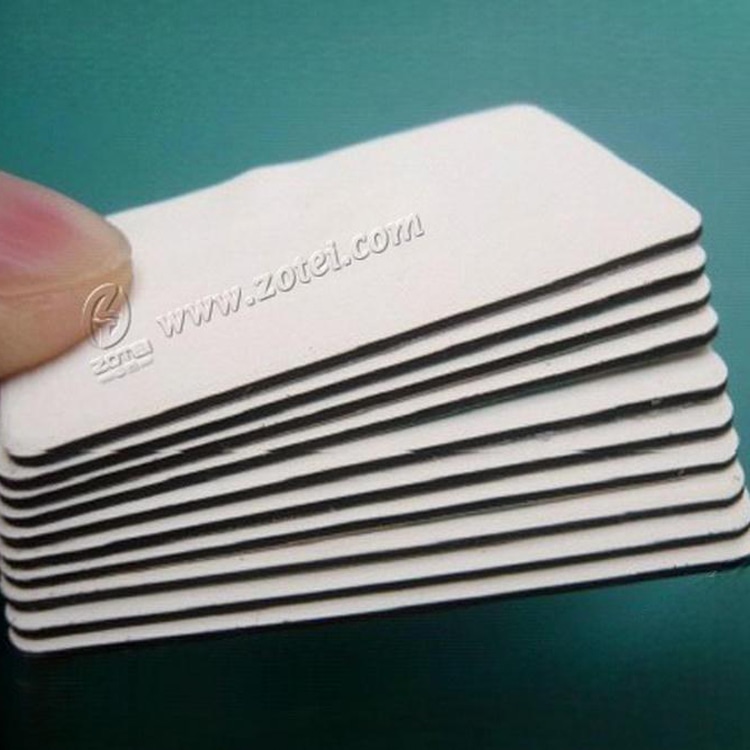 Близък план на подредени PVC RFID тагове за метал със заоблени ъгли и многослойна антиметална подложка върху тюркоазена повърхност.