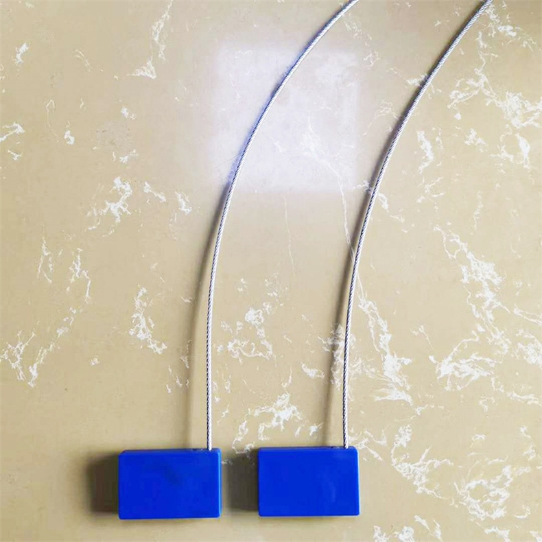 Две сини RFID пломби за сигурност SS4428-1 са подравнени с прави изправени стоманени жици върху светла мраморна повърхност.