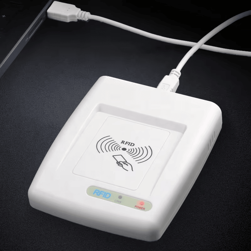 Тази снимка показва HF RFID четеца RC200U свързан чрез USB кабел на бюро за да демонстрира захранена работа и връзка за данни.