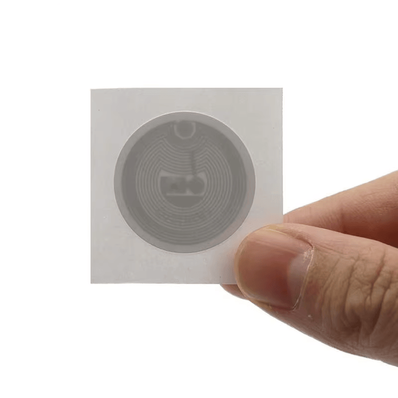 Подробна илюстрация на функционалните слоеве на HF RFID етикет, включително печатна повърхност и висококачествен лепилен гръб.